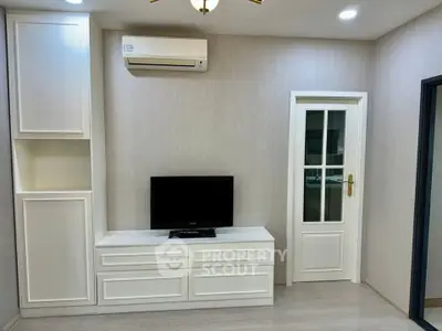 Modern living room with sleek white cabinetry and mounted air conditioning unit.