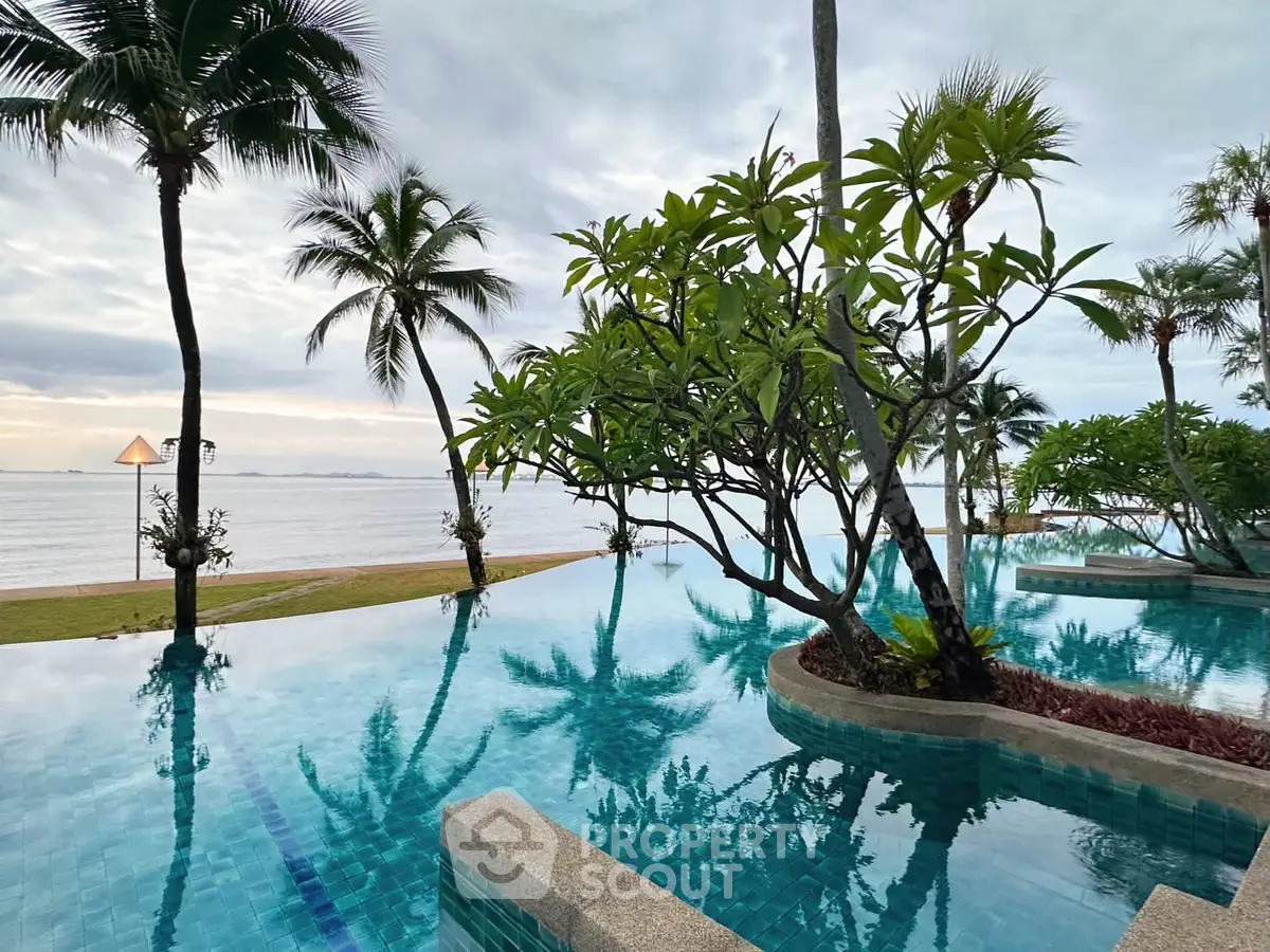 Stunning beachfront pool with palm trees and ocean view, perfect for luxury living.