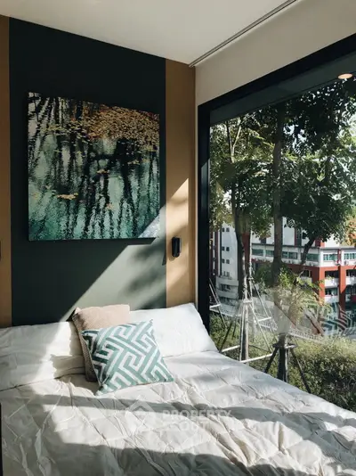 Modern bedroom with large window and stylish decor overlooking lush greenery.