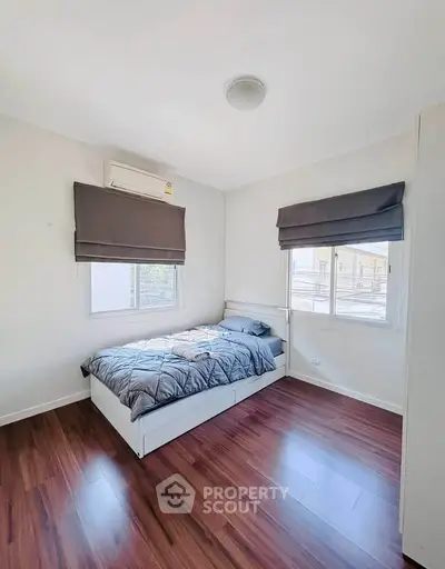 Bright and cozy bedroom with wooden flooring and ample natural light.