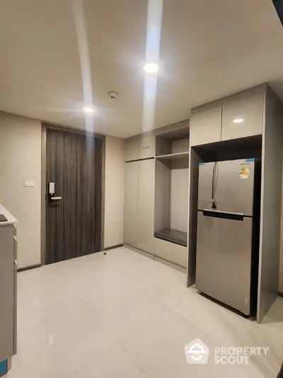 Modern kitchen with sleek cabinetry and stainless steel fridge in a stylish apartment.