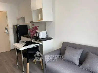 Modern compact living room with kitchenette, featuring sleek design and cozy seating area.