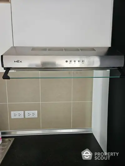 Modern kitchen with sleek stainless steel range hood and glass shelf