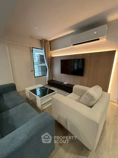 Modern living room with stylish furniture and wall-mounted TV, featuring sleek air conditioning unit.