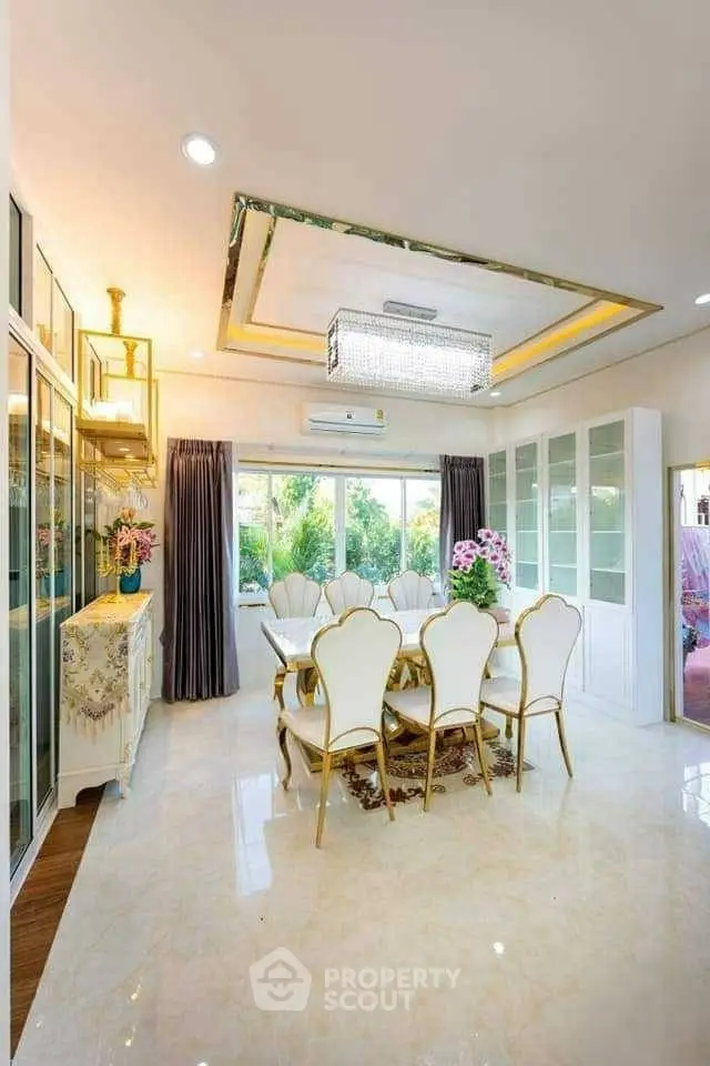 Luxurious dining room with elegant chandelier and garden view, featuring opulent decor and large windows.
