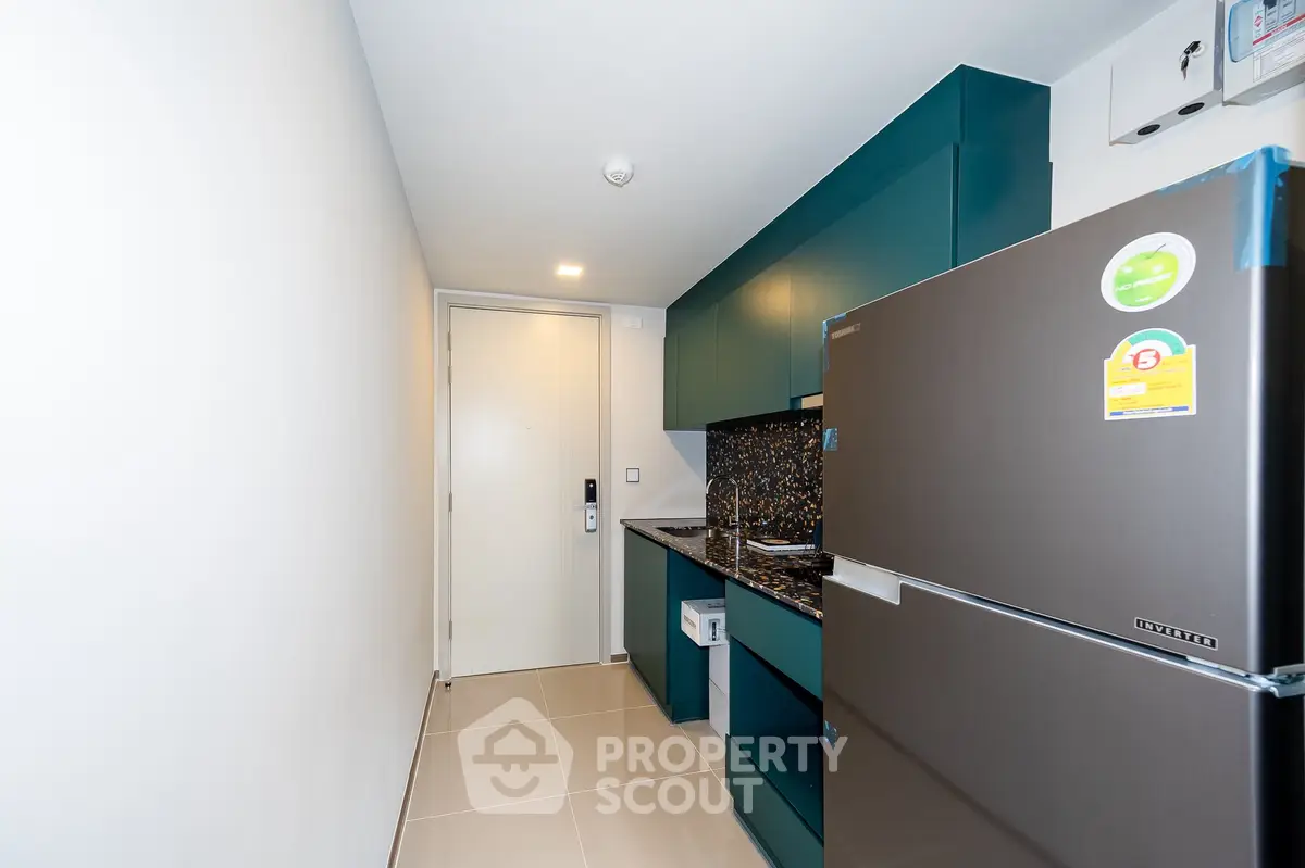 Modern kitchen with sleek cabinetry and stainless steel fridge in compact layout.