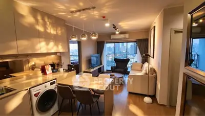 Modern open-plan living room with city view, featuring stylish furniture and integrated kitchen appliances.