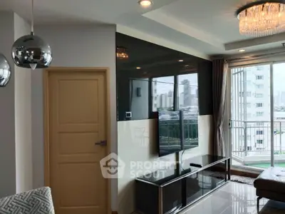 Modern living room with sleek TV setup and balcony view in high-rise apartment.