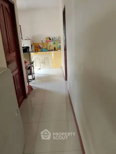 Bright hallway leading to a cozy kitchen with yellow tiles and modern appliances.