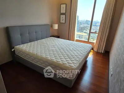Spacious bedroom with city view and elegant decor, featuring a large bed and floor-to-ceiling window.