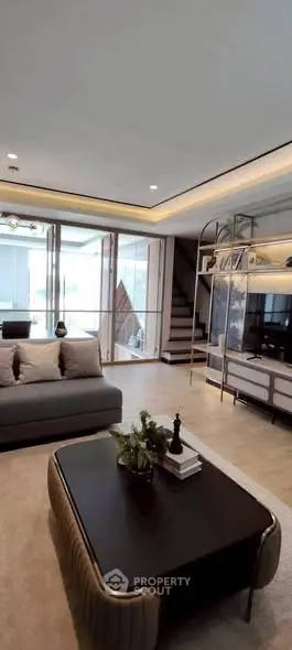 Luxurious modern living room with elegant decor and large windows offering natural light.