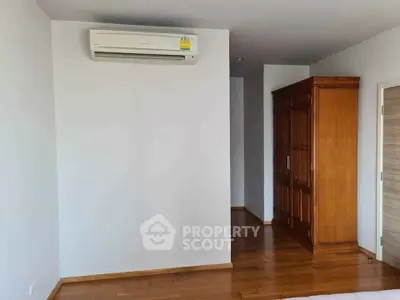 Spacious bedroom with wooden flooring and air conditioning unit