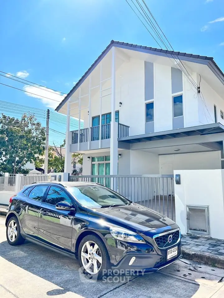 Modern two-story house with sleek design and car parked in driveway under clear blue sky.