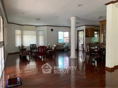 Spacious living room with elegant wooden flooring and classic furniture in a well-lit home.