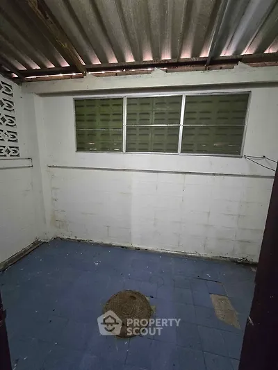 Small storage room with blue tiled floor and corrugated metal roof.