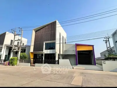 Modern industrial building with unique architectural design and spacious parking area.