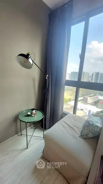 Cozy reading nook with city view, featuring a stylish floor lamp and comfortable seating.