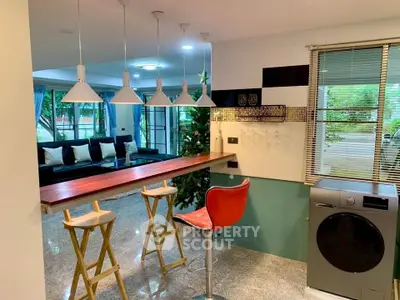 Modern open-plan living room with stylish kitchen bar and washing machine