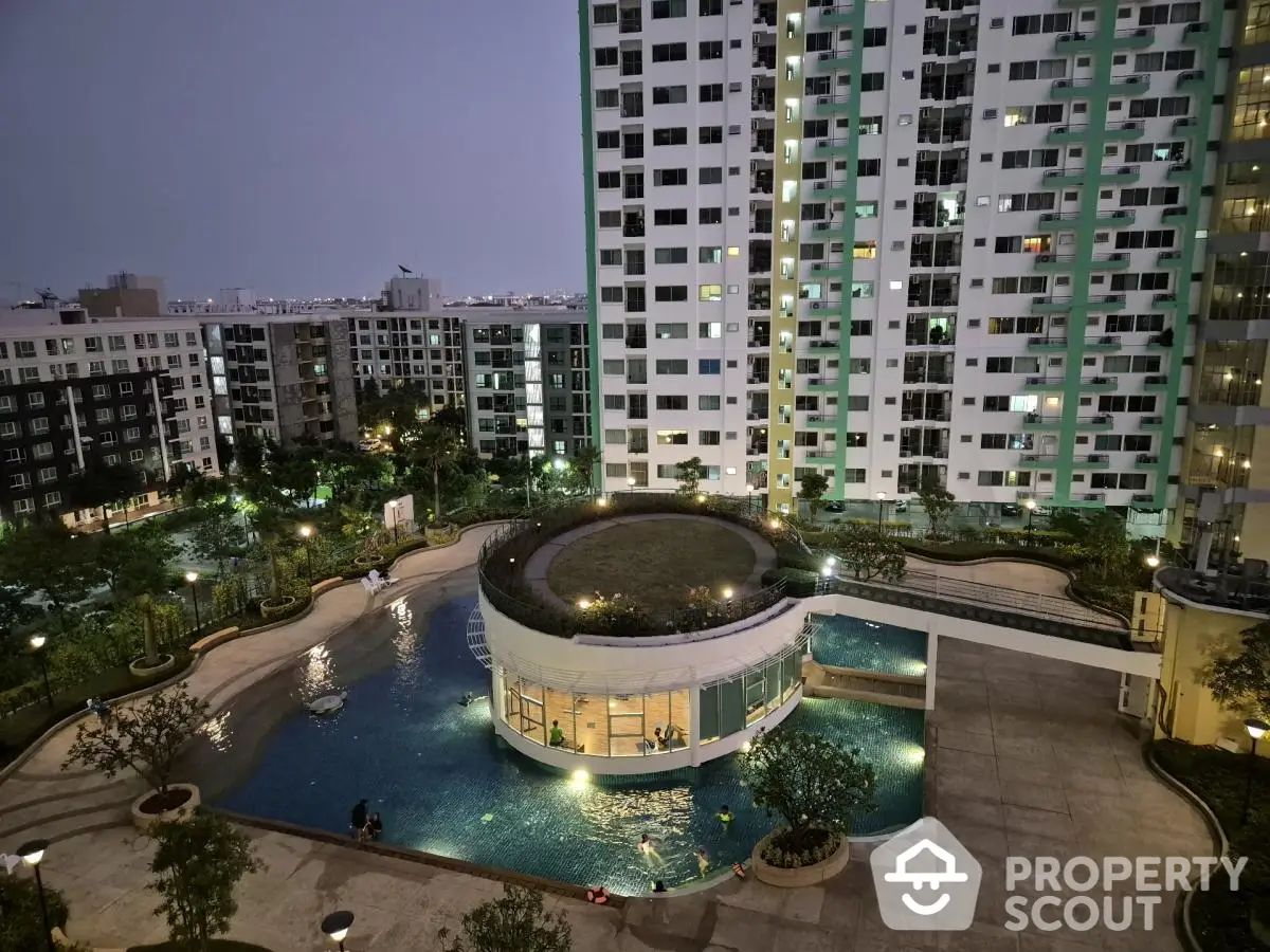 Modern high-rise apartment complex with illuminated pool and landscaped garden at dusk.