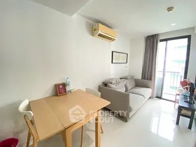 Modern living room with cozy sofa, dining table, and balcony access in a bright apartment.
