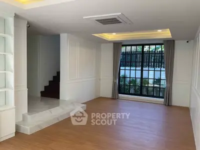 Spacious living room with large window and elegant wooden flooring