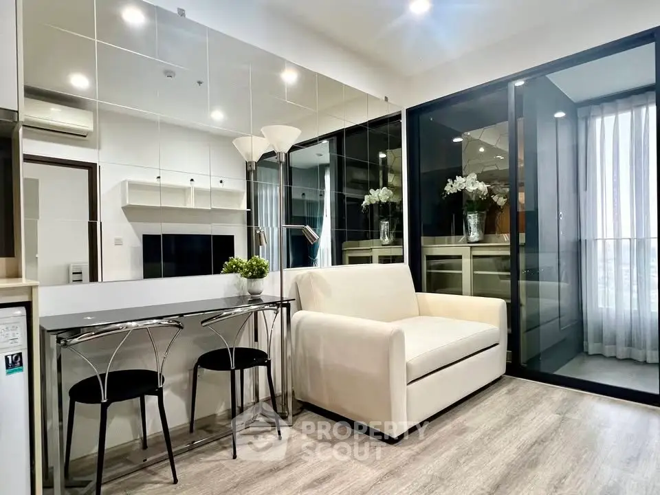 Modern living room with sleek design and mirrored wall, featuring a cozy sofa and stylish dining area.