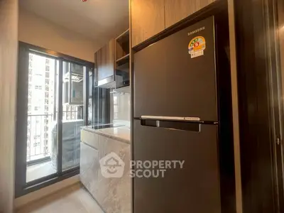 Modern kitchen with sleek appliances and balcony view in urban apartment.