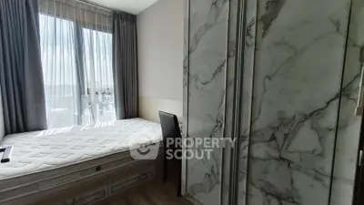 Modern bedroom with large window and marble accents, offering a bright and stylish living space.