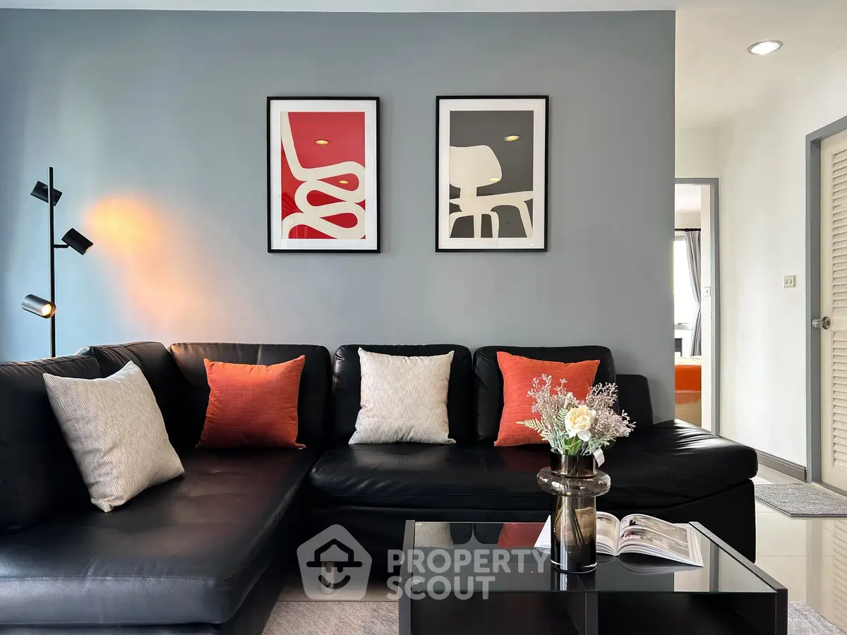 Stylish modern living room with black leather sofa and chic wall art, perfect for urban living.