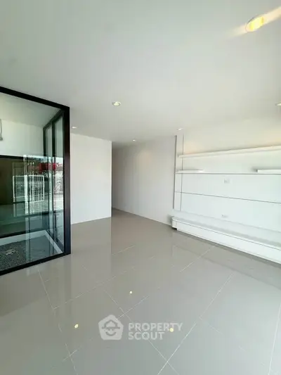 Spacious modern living room with sleek white shelving and glossy tiled floors.