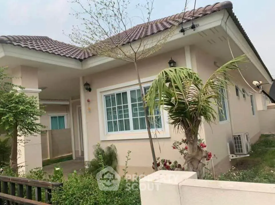 Charming single-story house with tiled roof and lush garden, perfect for family living.