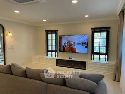 Modern living room with cozy gray sofa and large wall-mounted TV, perfect for relaxation.