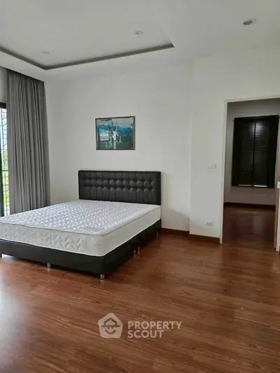 Spacious bedroom with modern decor and large window for natural light.