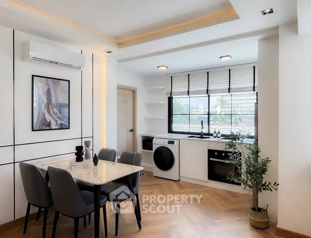 Modern dining area with stylish kitchen featuring built-in appliances and natural light.