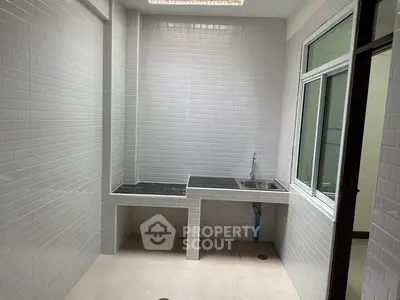Spacious utility room with modern tiled walls and built-in sink, perfect for laundry or storage.