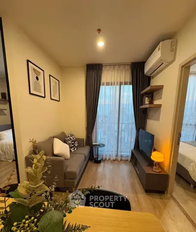 Modern living room with cozy decor and city view, featuring a comfortable sofa and wall-mounted TV.