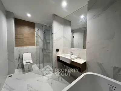 Luxurious modern bathroom with marble tiles and glass shower enclosure