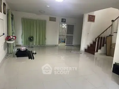 Spacious empty living room with staircase and tiled flooring