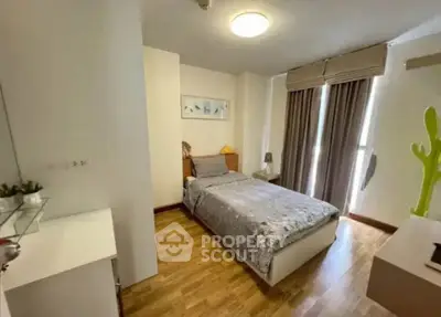 Cozy bedroom with wooden flooring and large window for natural light