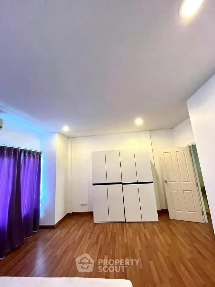 Spacious bedroom with modern wardrobe and wooden flooring