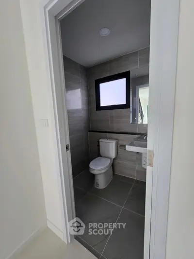 Modern bathroom with sleek design and neutral tones, featuring a window for natural light.