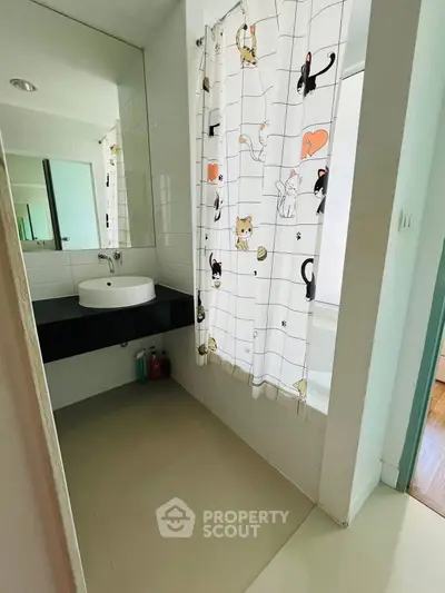 Charming bathroom with playful cat-themed shower curtain and modern sink design.