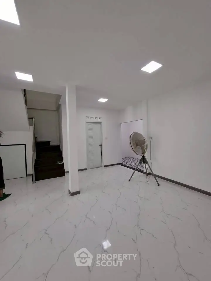 Spacious minimalist interior with modern lighting and sleek flooring, ideal for versatile living space.