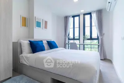Modern bedroom with large windows and stylish decor in a bright apartment.