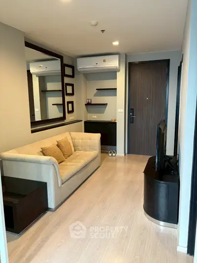 Modern living room with cozy sofa and wall-mounted TV, featuring sleek wooden flooring and stylish decor.