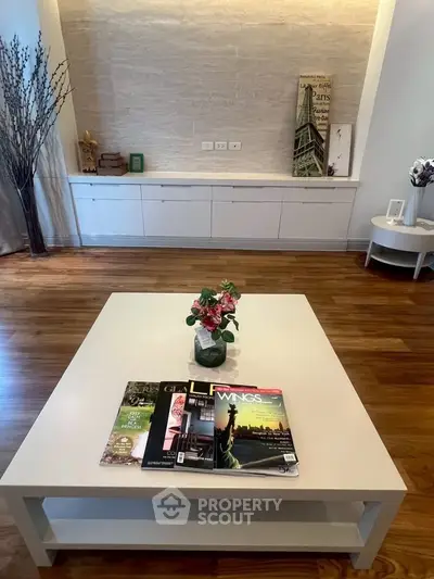 Stylish living room with elegant decor and hardwood floors, featuring a modern coffee table and chic magazines.