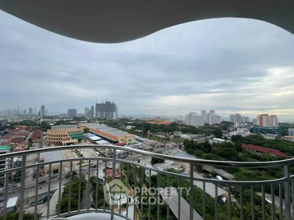 Stunning cityscape view from a high-rise balcony with lush greenery and urban skyline.