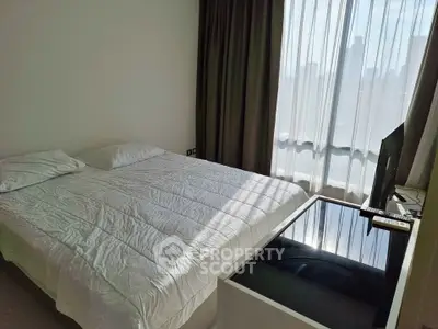 Modern bedroom with large window and natural light, featuring a comfortable bed and sleek furnishings.