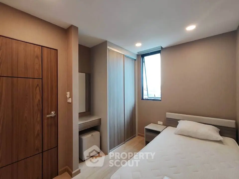 Modern bedroom with sleek design and ample natural light, featuring a comfortable bed and stylish wooden accents.
