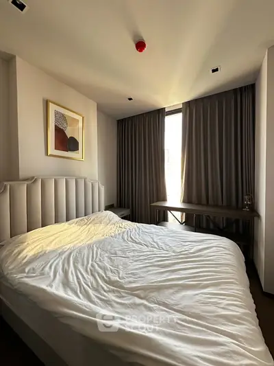 Cozy bedroom with modern decor and large window offering natural light.